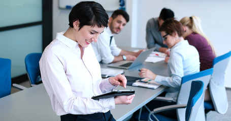 Obraz premium Portrait of smiling casual businesswoman using tablet with coworkers standing in background
