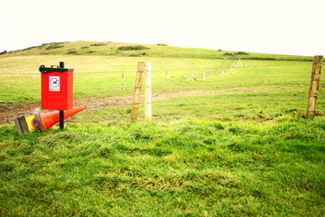 The red color dustbin in the field.