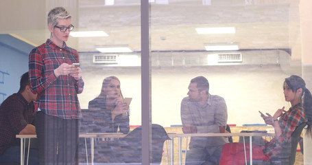 Business Woman Looking Through A Window And using On A Cell Phone during bussines meeting
