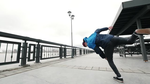 Slow-motion Acrobatics - teenager performing acrobatics flips and somersault at promenade