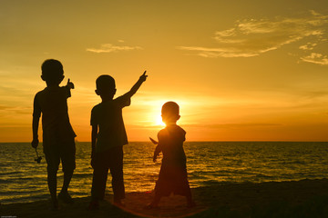 Silhouette of kids enjoying thier time at beach during sunset