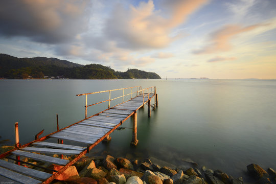 Long exposure shot of abandoned pier at seascape during dusk time.