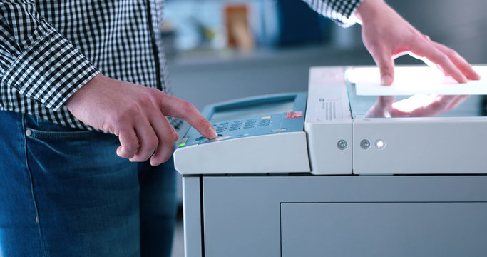 Male Assistant Using Copy Machine In Modern Office