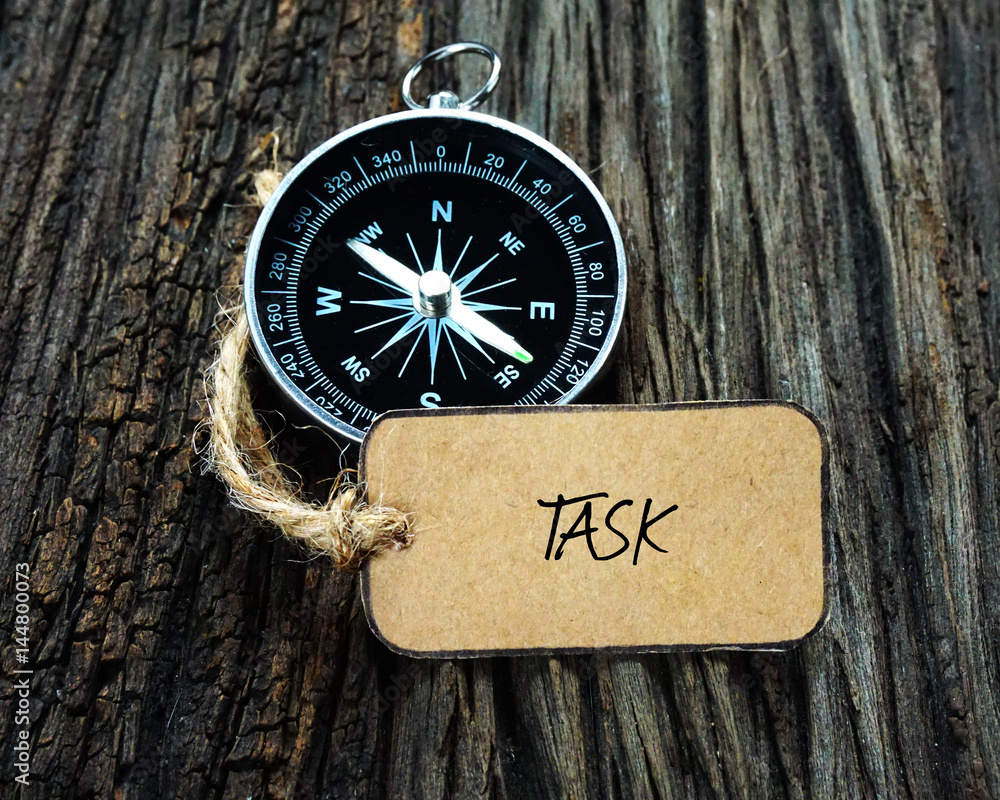 Wall mural compass and paper tag written with task on wooden background.