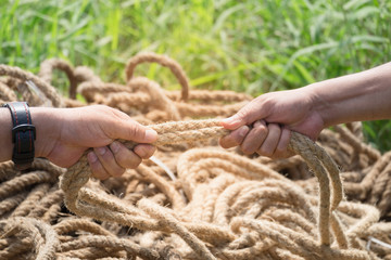 Two people are pulling a rope competing hands.