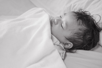 Obraz premium Closeup sick child sleep on hospital bed textured background in black and white tone