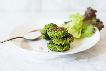 falafel di piselli e foglie di lattuga su piatto bianco; sfondo sfocato