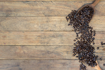 Coffee beans in an old wooden scoop on wooden background