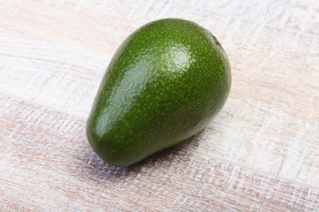 Fresh, green Avocado isolated on wooden background.