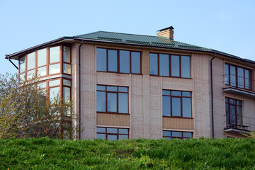 Metal roofing. Large modern house with large windows and balconies. Rain gutter on the roof top of house. metal roof. Chimney pipe.