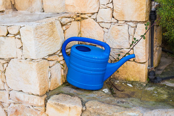 Concept of gardening. Blue watering can outdoor