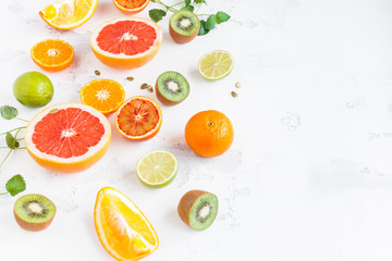 Fruit background. Colorful fresh fruit on white table. Orange, tangerine, lime, kiwi, grapefruit
