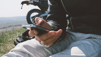 using phone in nature. Close-up of the phone in a hands-on background with motorcycle. Lifestyle...