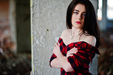 Fototapeta premium Portrait girl with red lips wearing a red checkered shirt with bare shoulders posed sexy background abadoned place.