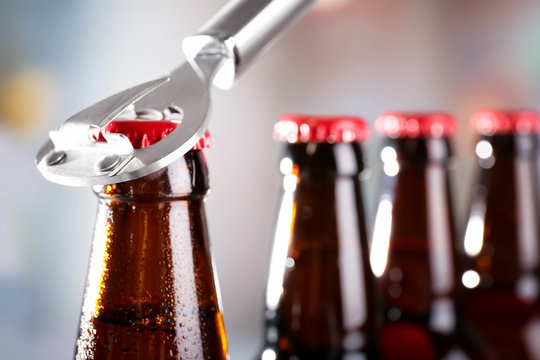 Bottles of beer with opener on blurred background