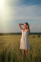 Fototapeta na wymiar Beautiful summer girl in the field. The sun's rays and rain. Happy young woman laughing