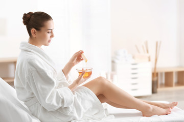 Woman holding bowl with hot wax in spa center