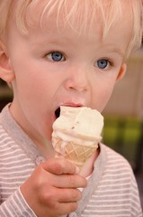 Closeup-portrait of cute blond boy who licks ice-cream. Child concept.