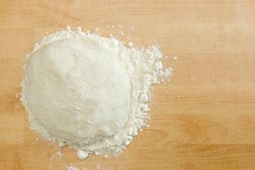 Ball of dough on wooden background with dusting of flour