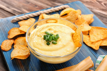 Bowl with beer cheese dip and chips on wooden board