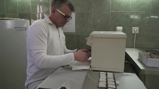 Male laboratory technician using equipment to analysis a tissue samples, concept pathological analysis, crane shot from young man portrait low angle to high angle view, interior scene