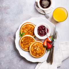 Healthy breakfast with fresh hot pancakes with berry jam on light gray background, top view.