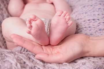 Baby feet in mother hands. Tiny Newborn Baby's feet on female Shaped hands closeup. Mom and her Child.
