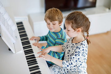 Two little kids girl and boy playing piano in living room or music school © Irina Schmidt
