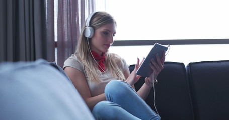 Obraz premium Lovely Blond Woman Listening To Music while resting on couch