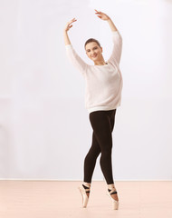 Obraz premium Ballet art concept. Young beautiful ballerina training in dance hall