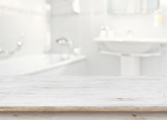 Wooden table in front of blurred bathroom interior as background