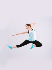 Young beautiful fitness girl training on light background