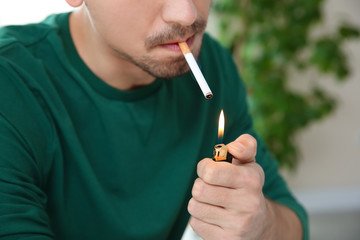 Young man lighting cigarette, closeup