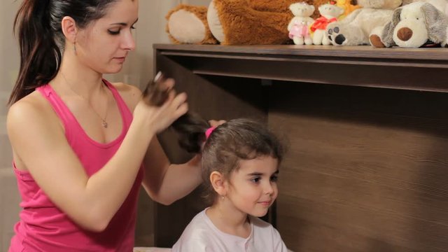 Mother removes an scrunchy from the head of the beautiful curly girl. Preparation for a dream.