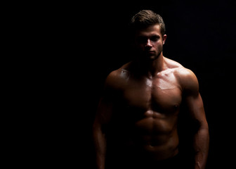Fototapeta premium Horizontal portrait of a handsome young muscular fit and toned man posing confidently on black background copyspace workout crossfit fitness athleticism physique endurance confidence motivation.