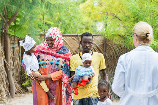 Caucasian woman doctor with African black family outdoors