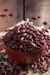 Red beans in a cup with a wooden sign on the wooden floor.