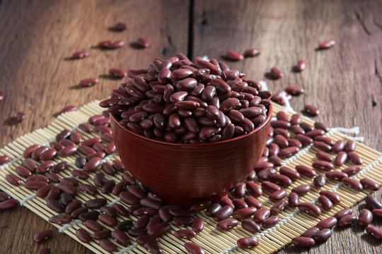 Red beans in a cup with a wooden sign on the wooden floor.