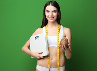 Beautiful young woman with coconut and scales on color background