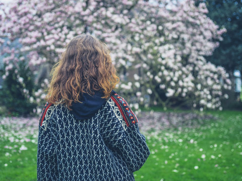 Young woman standing by magnolia tree in park