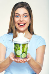 Smiling woman holding blender with smoothy ingredients.