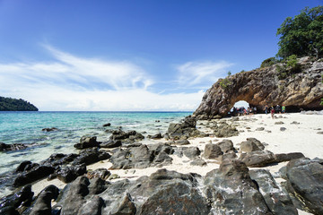 rocks with sand at coastline with bright sunlight in blue sky