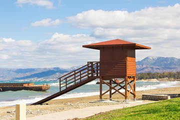 Red wooden lifeguard hut on an empty morning beach