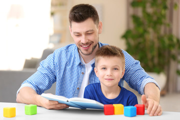 Dad and son reading interesting book at home