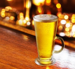 Glass of beer with bar scene in the background