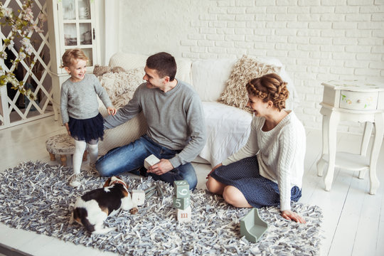 happy family playing with a pet dog in the spacious living room