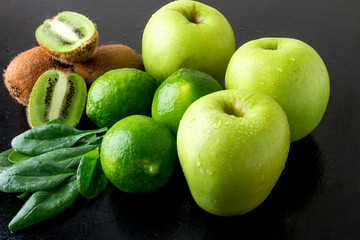 Ingredients for smoothie. Green fruits on black wooden background. Apple, lime, spinach, kiwi. Detox. Healthy food.