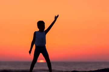 Fototapeta premium A Silhouette Of A Child Playing Near The Beach At Sunset