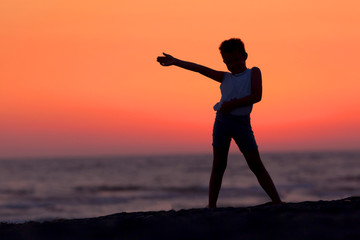 Fototapeta premium A Silhouette Of A Child Playing Near The Beach At Sunset