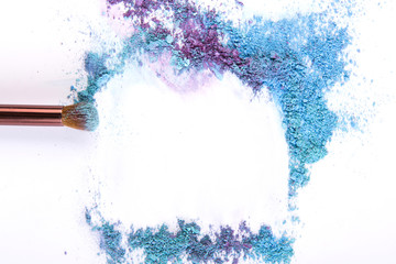Makeup brush background with eyeshadow sprinkled on white